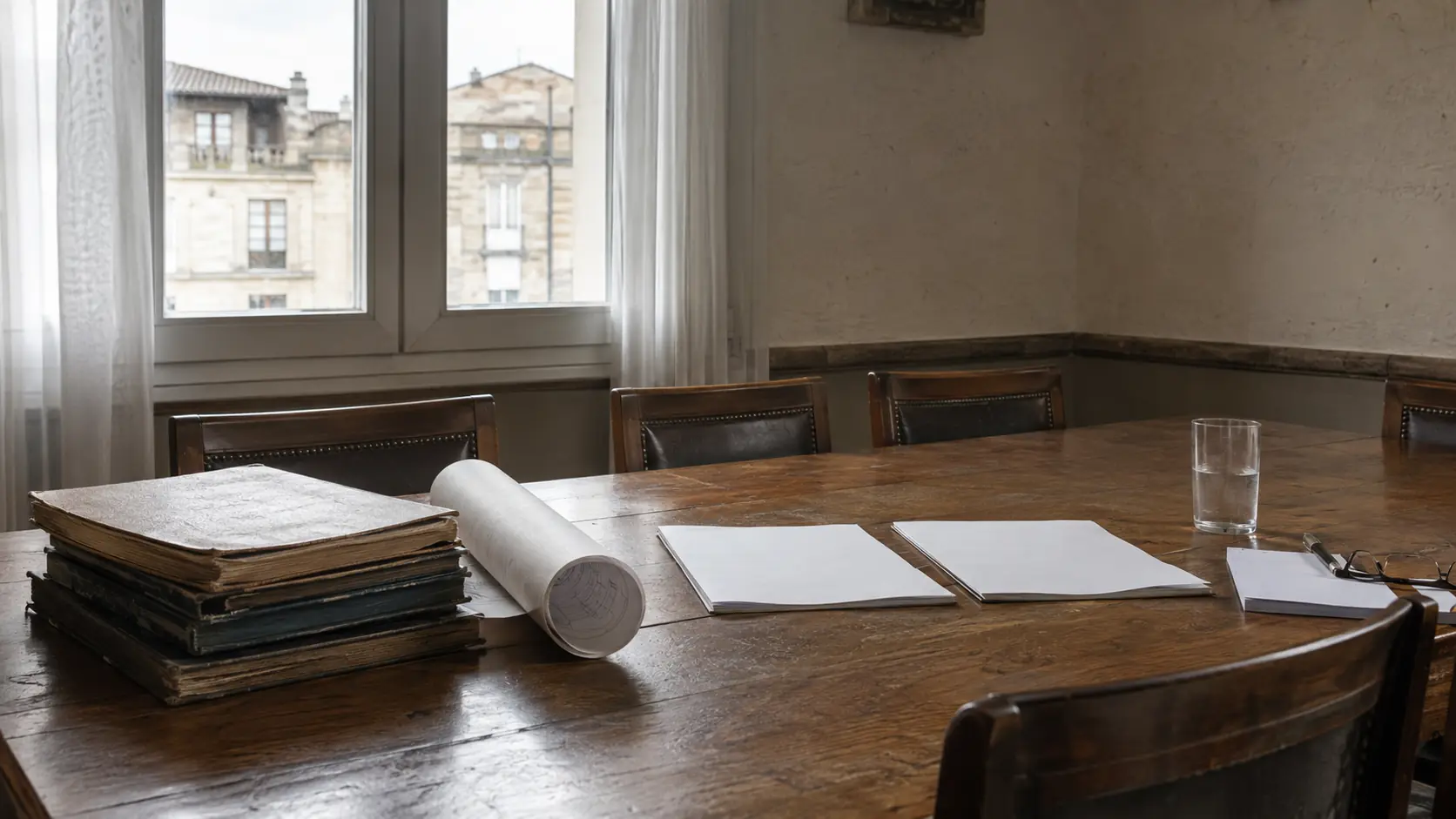 Mesa con planos de un edificio, un acta de comunidad y una carpeta de documentación técnica